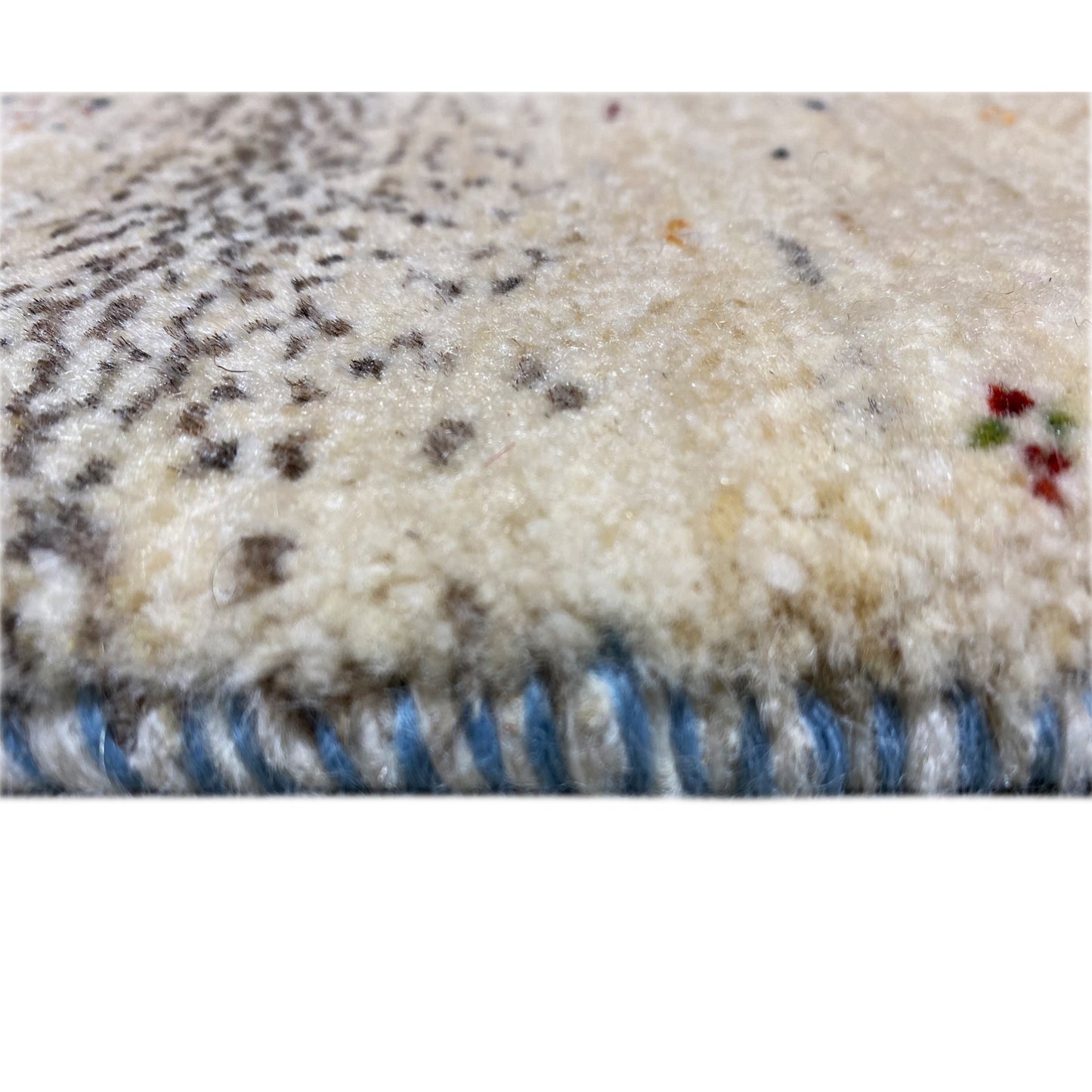 Nahaufnahme vom Teppichsaum: flauschiger Flor, Beige mit blauem Rand