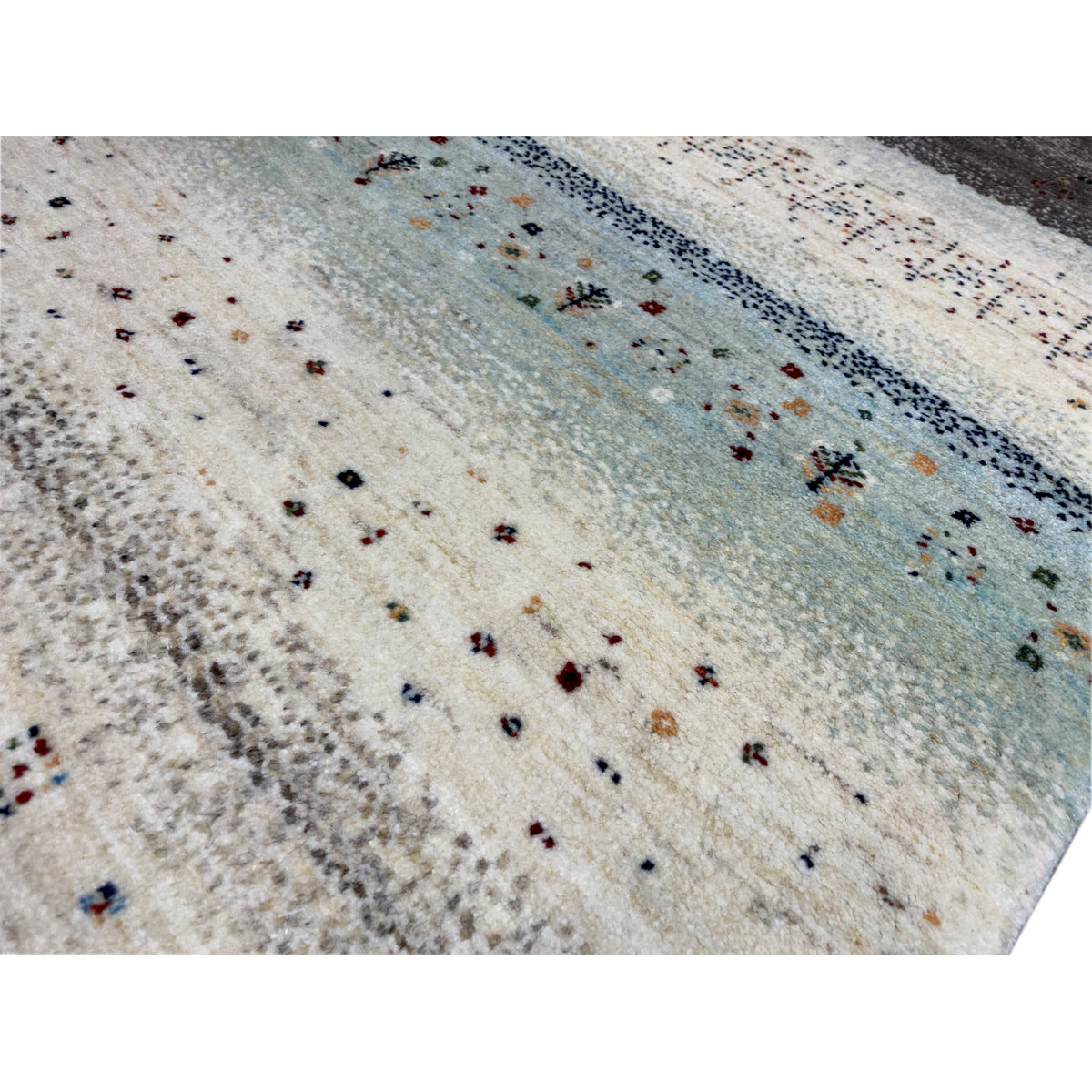 Nahaufnahme: Gabbeh-Teppich mit kurzem Flor, cremefarbener Fläche und kleinen Motiven