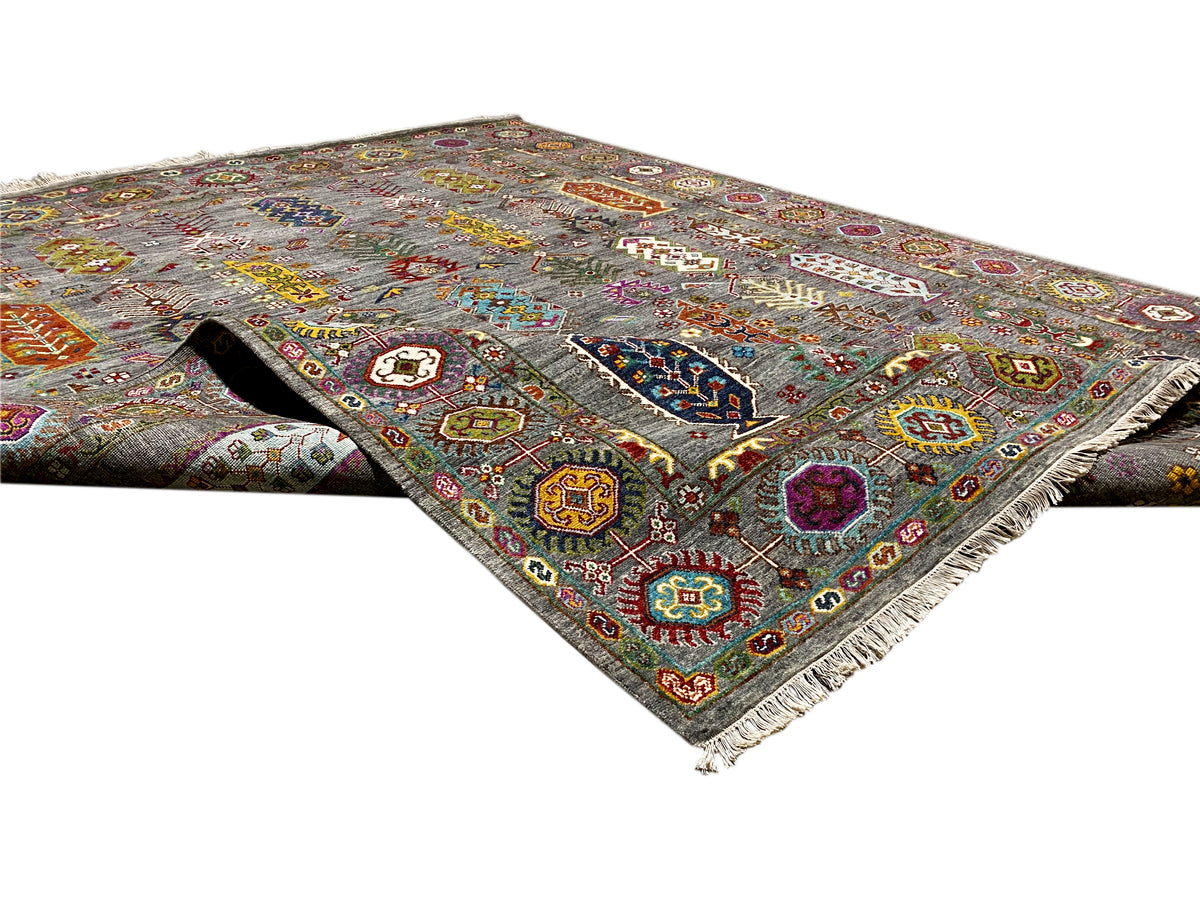Teppich diagonal ausgelegt: grauer Grund, bunte Ornamente, Zierbordüre und Fransen.