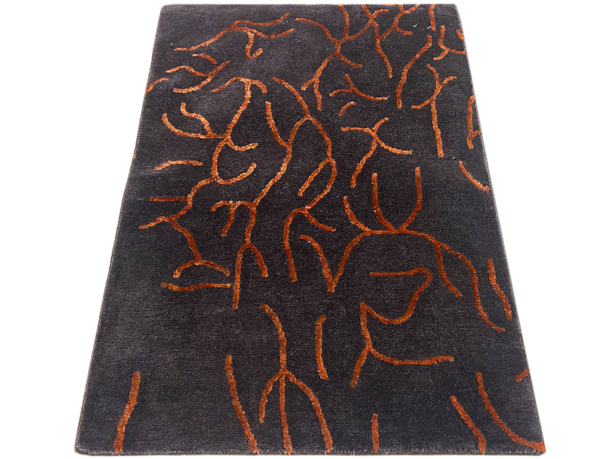 Rechteckiger Design-Teppich dunkelgrau mit orangefarbenem abstraktem Muster, schräg