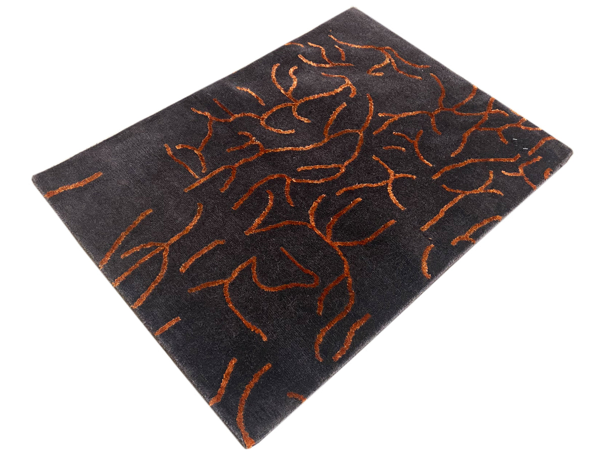 Design-Teppich dunkelgrau mit orangefarbenem abstraktem Muster, quadratisch aus Blickwinkel