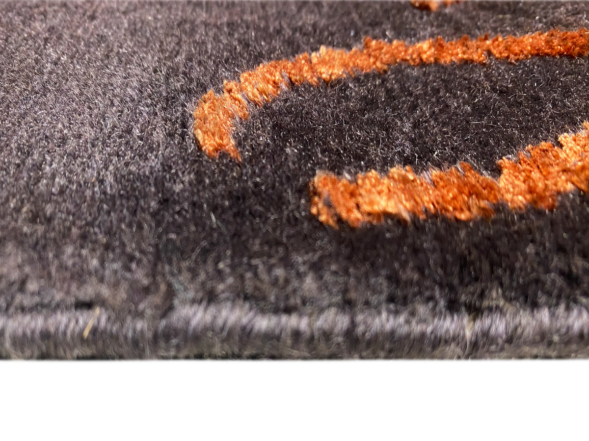 Teppichdetail: dunkelgrauer Flor mit orangefarbenen Hochflor-Applikationen