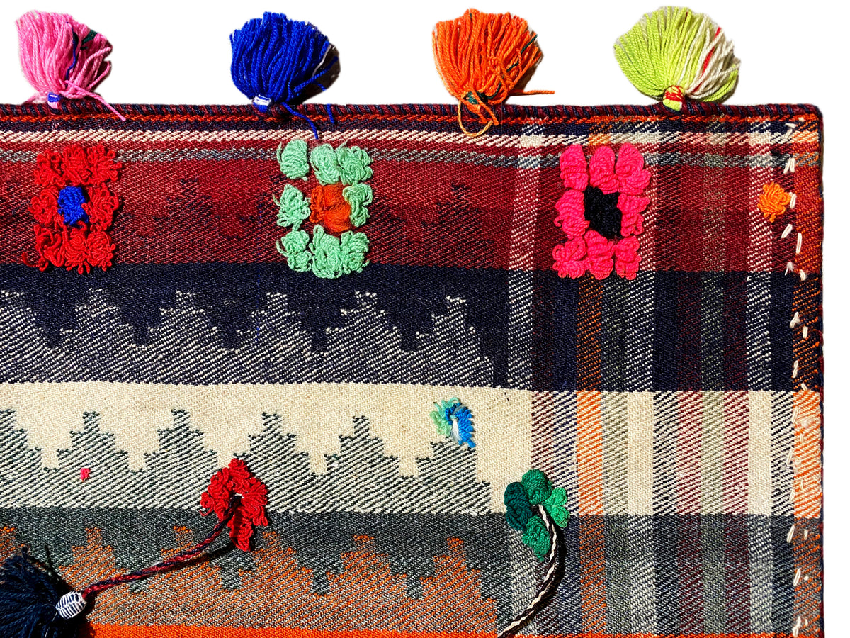 Nahaufnahme: Jajim-Teppich mit Karomuster, Blumenmotiven und mehrfarbigen Quasten