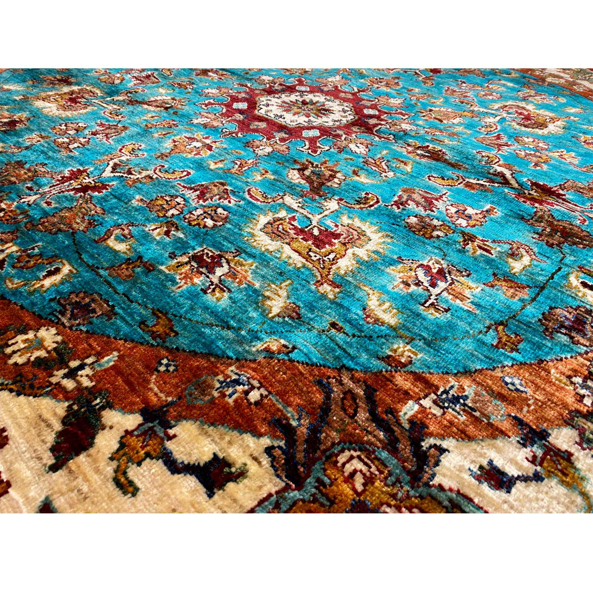 Teppichoberfläche mit türkisfarbenen Ornamente, beigen und braunen Farbakzenten