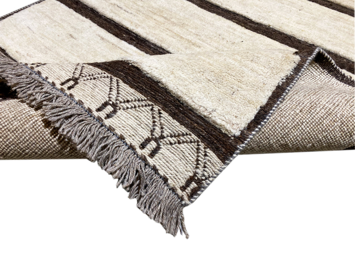 Eckdetail: eingewebte Ornamente und Fransen am Rand eines Kelim Teppichs