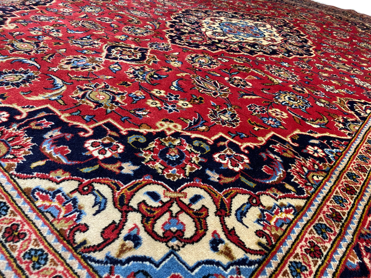 Nahaufnahme der Teppichoberfläche: rotes Feld mit blau-goldenen Ornamenten
