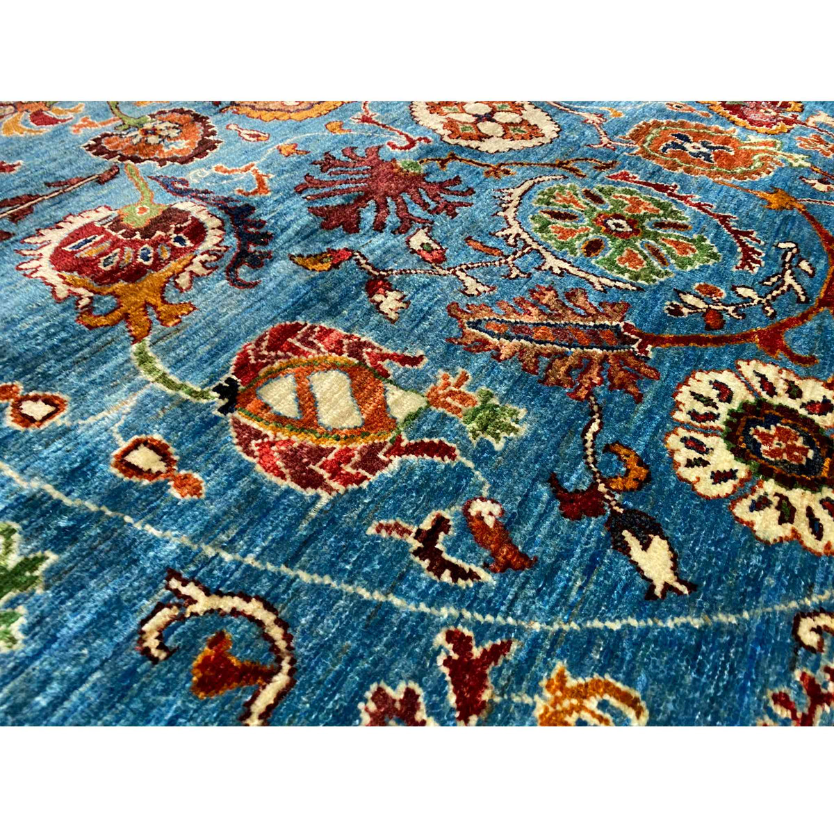 Nahaufnahme: Blauer Wollteppich mit mehrfarbigen Blumenmotiven und gewebter Textur