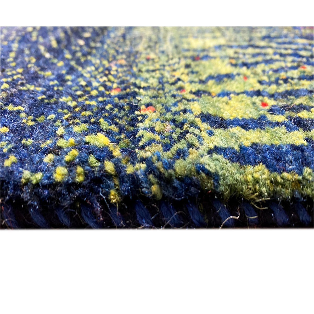 Teppichkante mit mehrfarbigen Pflanzenfeldern in Blau, Gelb und Grün