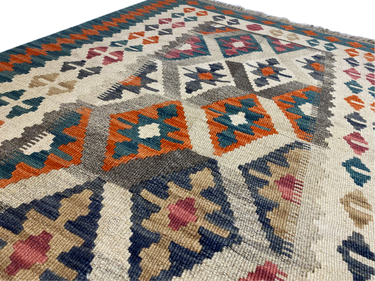Kelim-Teppich mit cremefarbenem Grund und bunten geometrischen Motiven, Rand mit Fransen