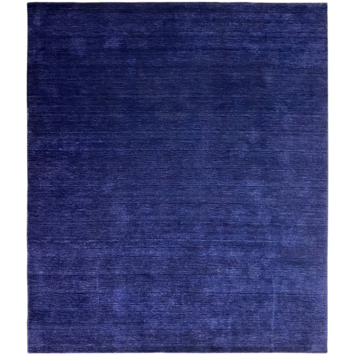 Blauer rechteckiger Teppich mit matter Oberfläche und feiner, subtiler Musterung.