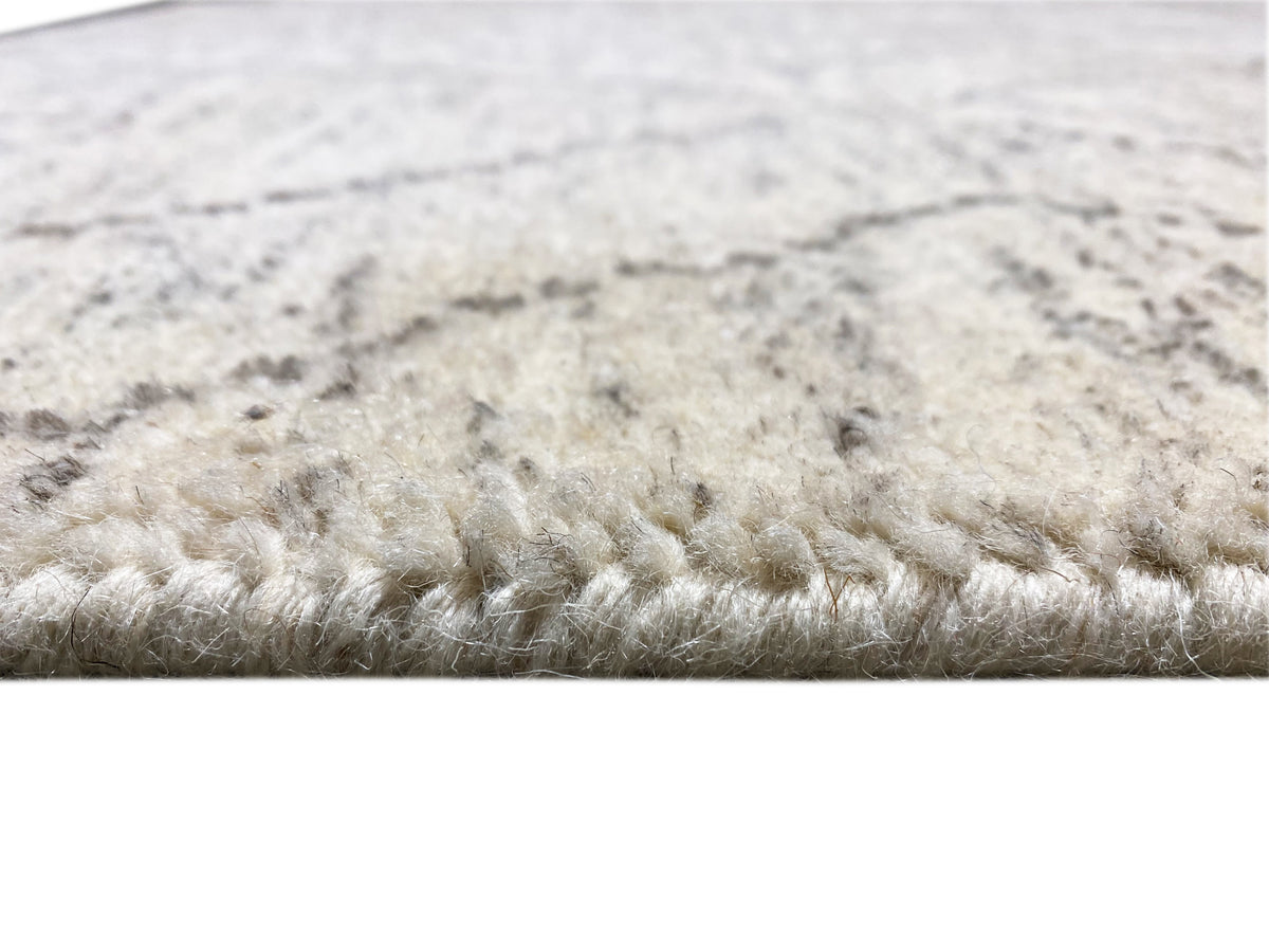 Nahaufnahme Teppichkante: dichter Flor in hellbeige mit grau gemasertem Muster