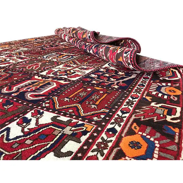 Bakhtiari-Teppich mit aufgerollter Ecke, bordeauxrote Farbfläche und detailreiche Muster