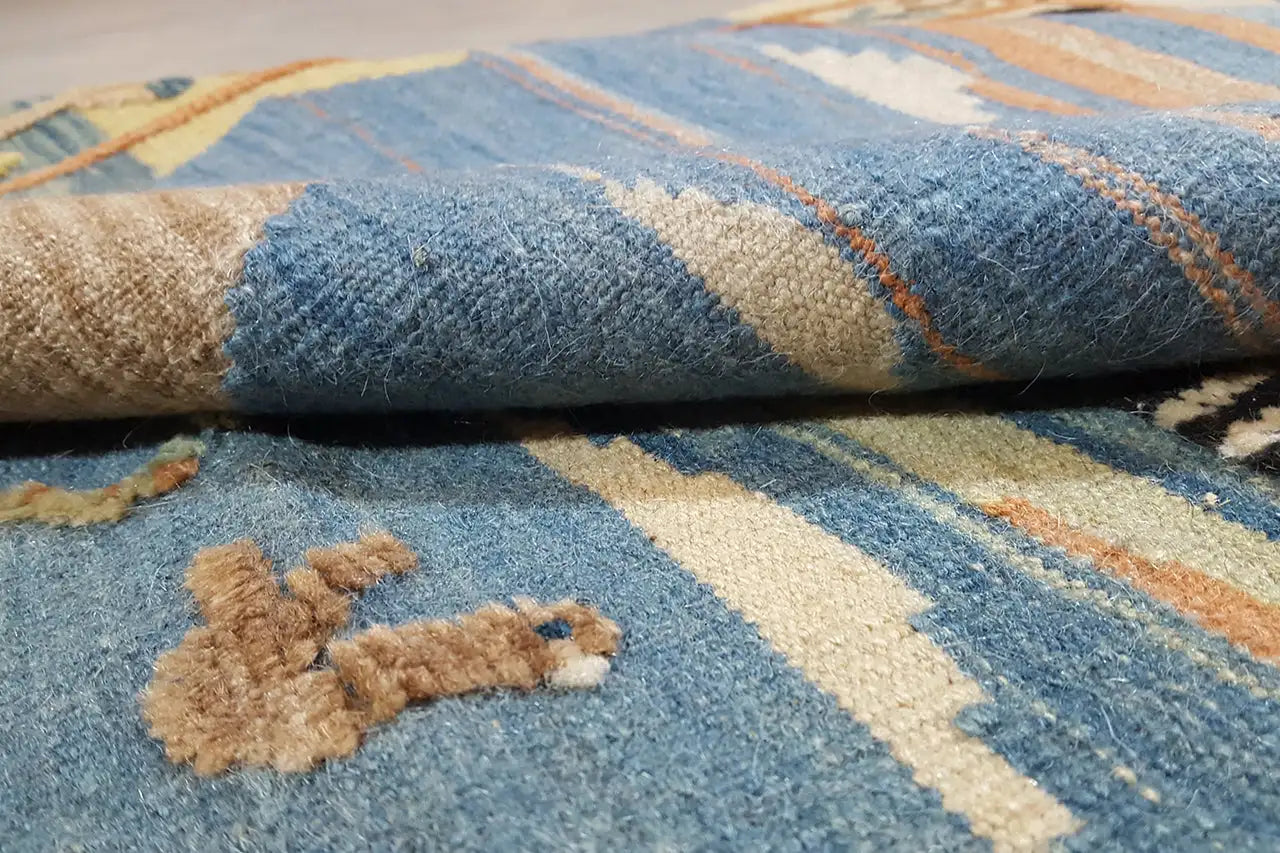 Nahaufnahme: blauer Kilim mit beigefarbenen Mustern und handgewebter Florstruktur