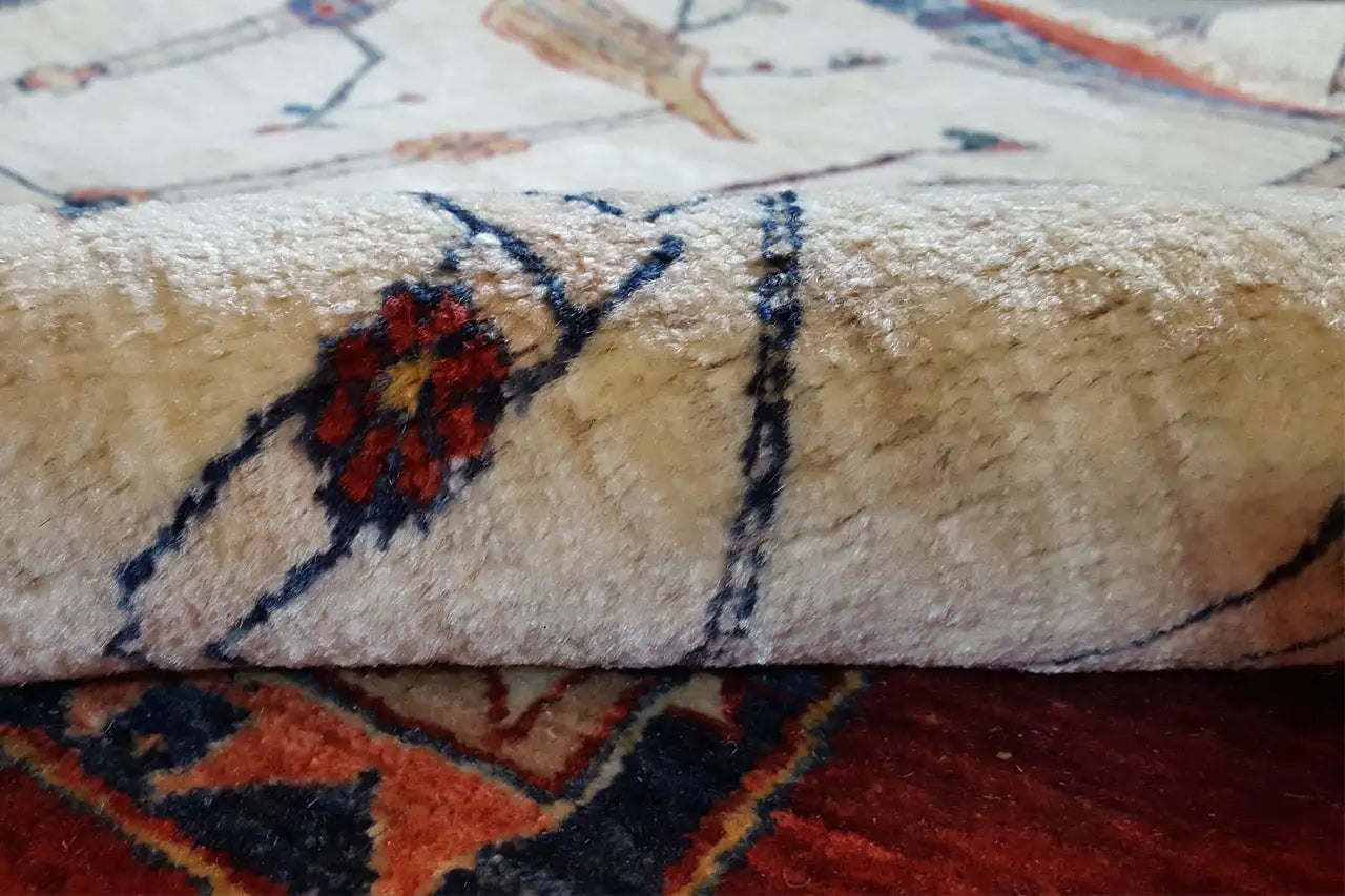 Teppichdetail: beiger Flor mit blauem Ornament und roter Blütenform