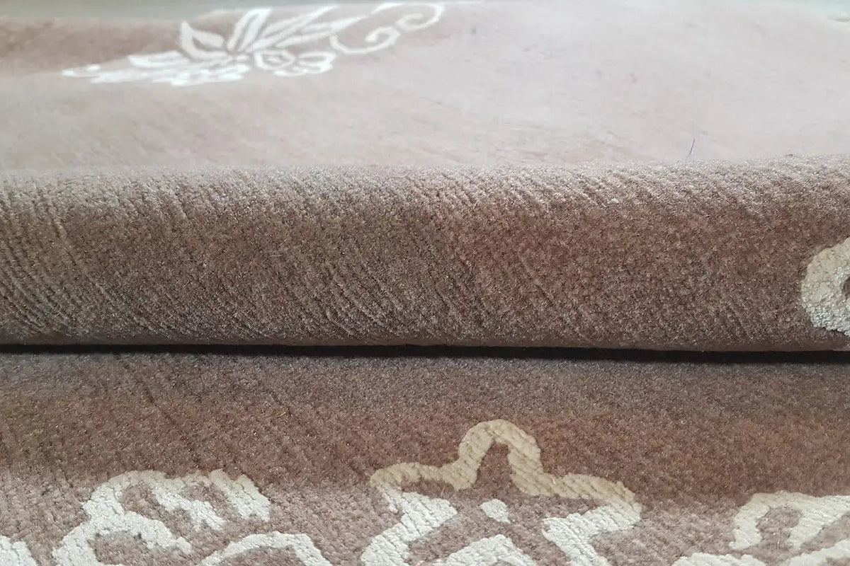 Designer-Teppich mit braunem Flor und cremefarbenem Ornamentmuster, gefaltet