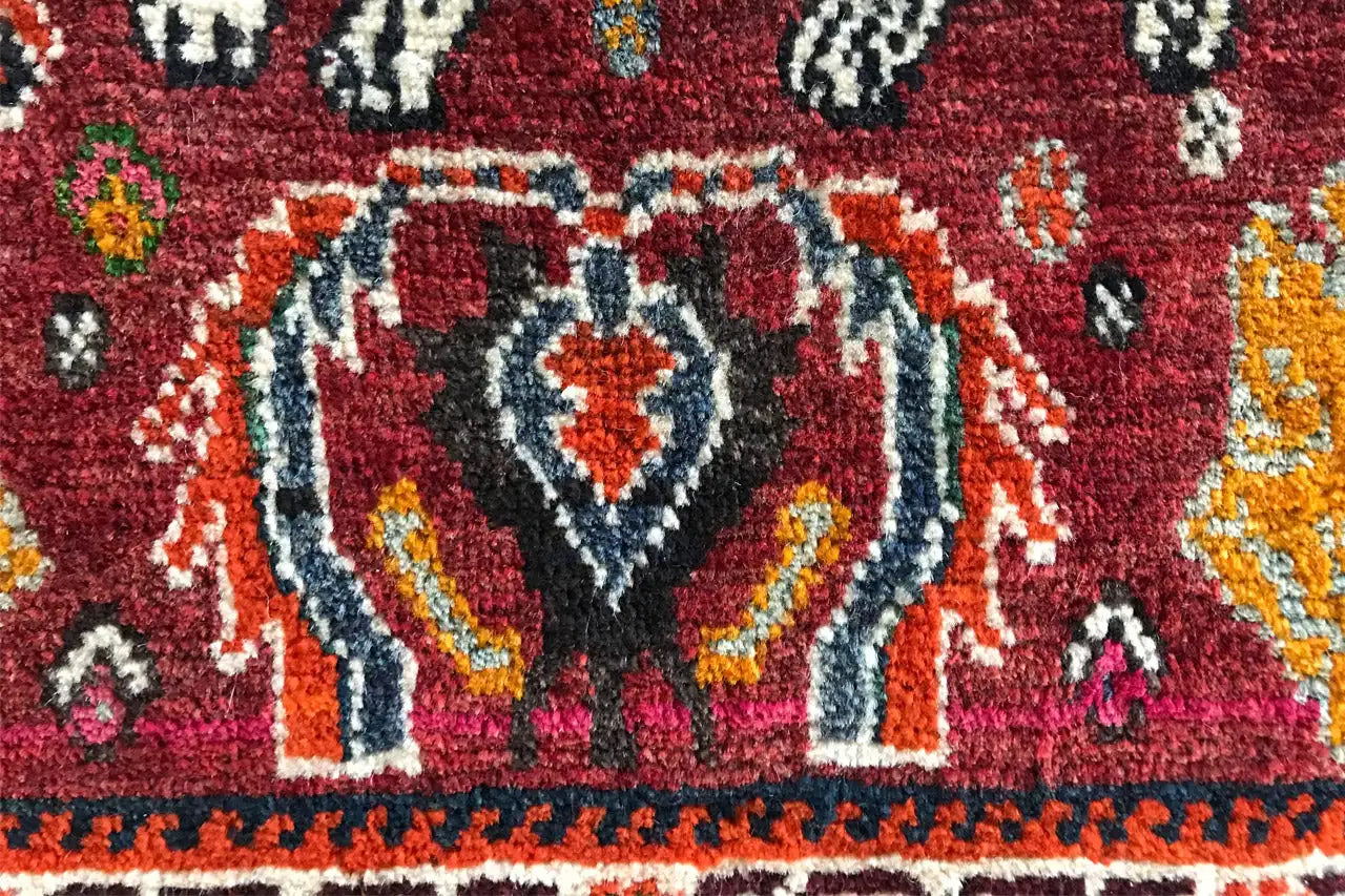 Teppichdetail mit stilisierter weißer Tierfigur und roten, blauen Ornamenten