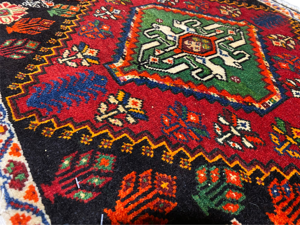 Poshti-Teppich Detailansicht einer Ecke: mehrfarbige geometrische Ornamente auf schwarzem Grund