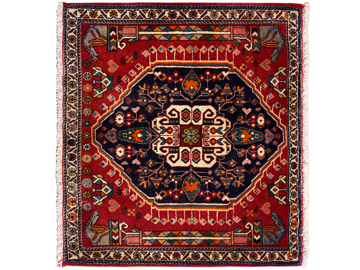 Teppich mit rotem Grund, dunkelblauem Medaillon und mehrfarbiger Bordüre, quadratisch
