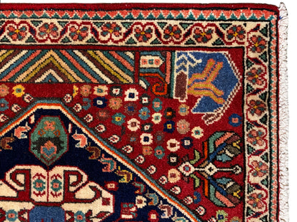 Teppichdetail: rotes Feld mit geometrischen Motiven, blaues Eckmotiv und Bordüre