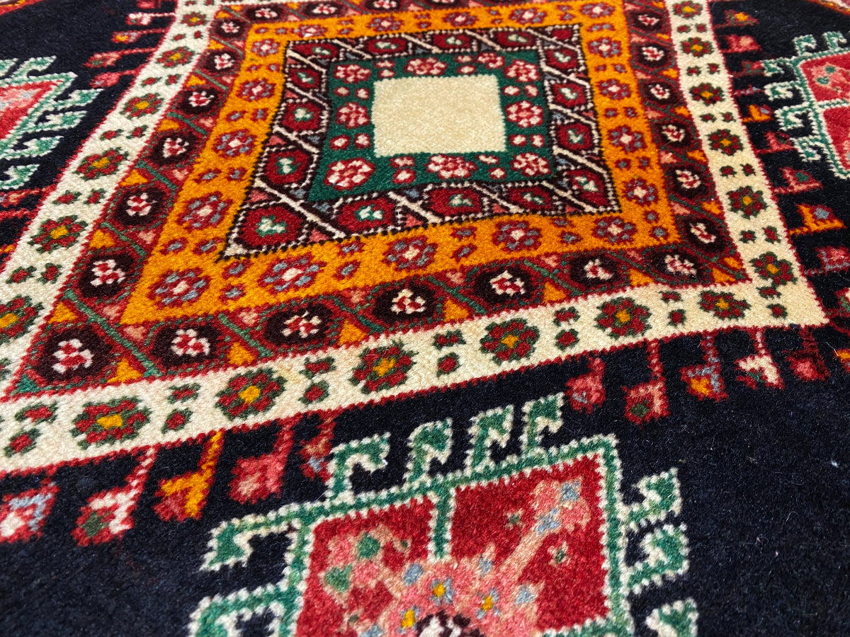 Poshti-Teppich Detailansicht mit orange-gelber Hauptraute, kleinen Ornamentelementen und weißer Mitte