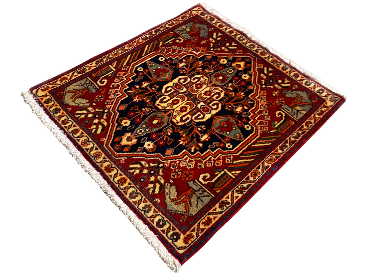 Teppich 65x59 cm mit rotem Hintergrund, dunklen Mittelornamenten und Fransen an den Kanten