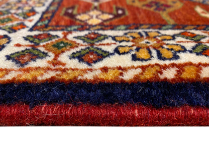 Teppichrand mit rotem Flor, dunkler Saumkante und ornamentalem Musterstreifen