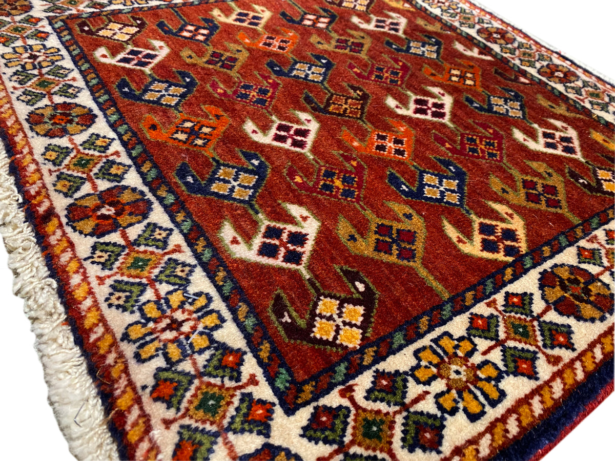 Teppich mit rotem Musterfeld, blau-türkisem Rahmen und ausgefranster Einfassung
