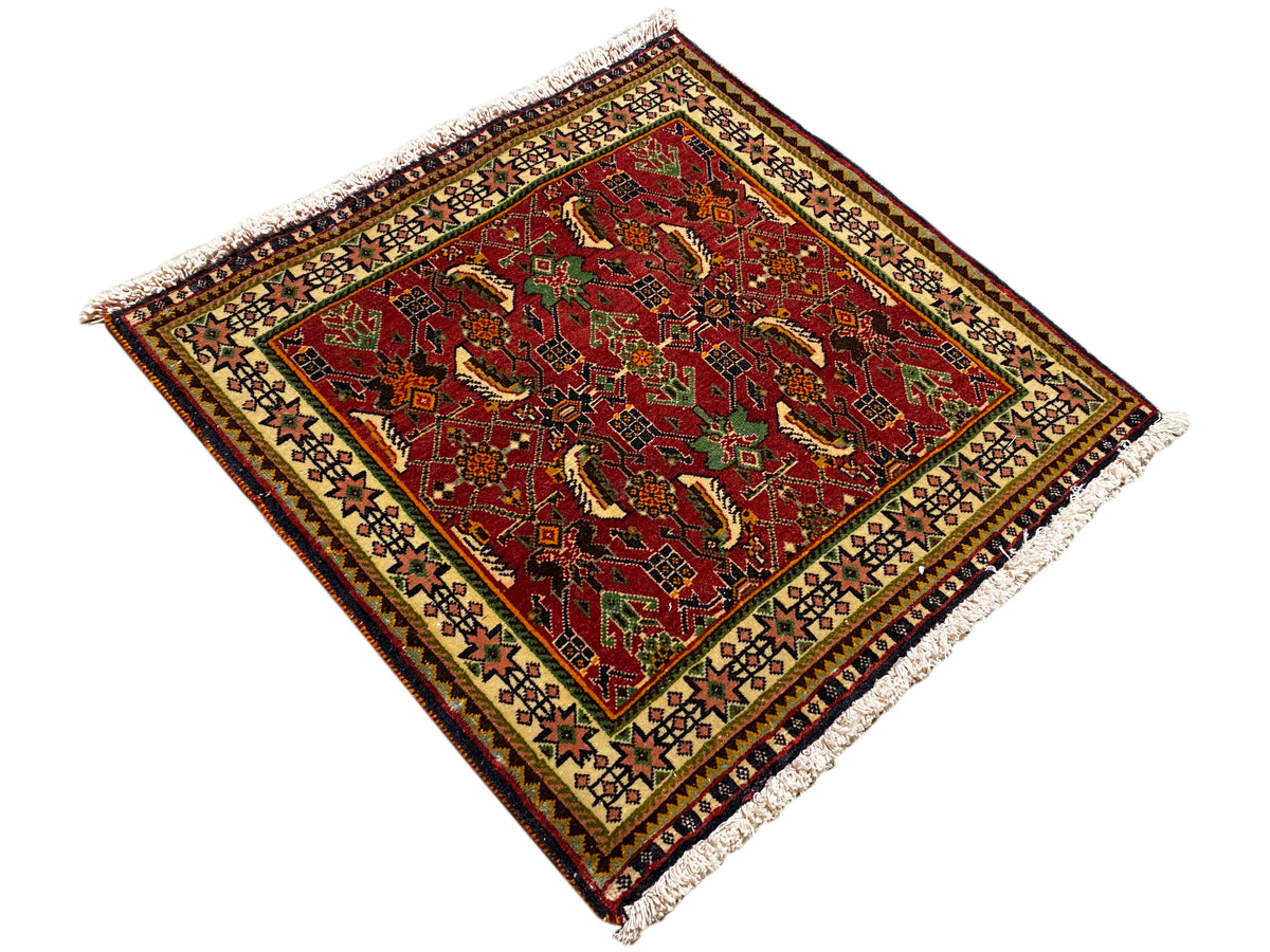 Poshti-Teppich 63x61 cm, diagonale Ansicht: rotes Muster mit grünen Details, Fransen.