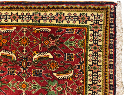 Poshti-Teppich 63x61 cm Detailansicht: rotes Ornamentfeld mit grünen und gelben Motiven.