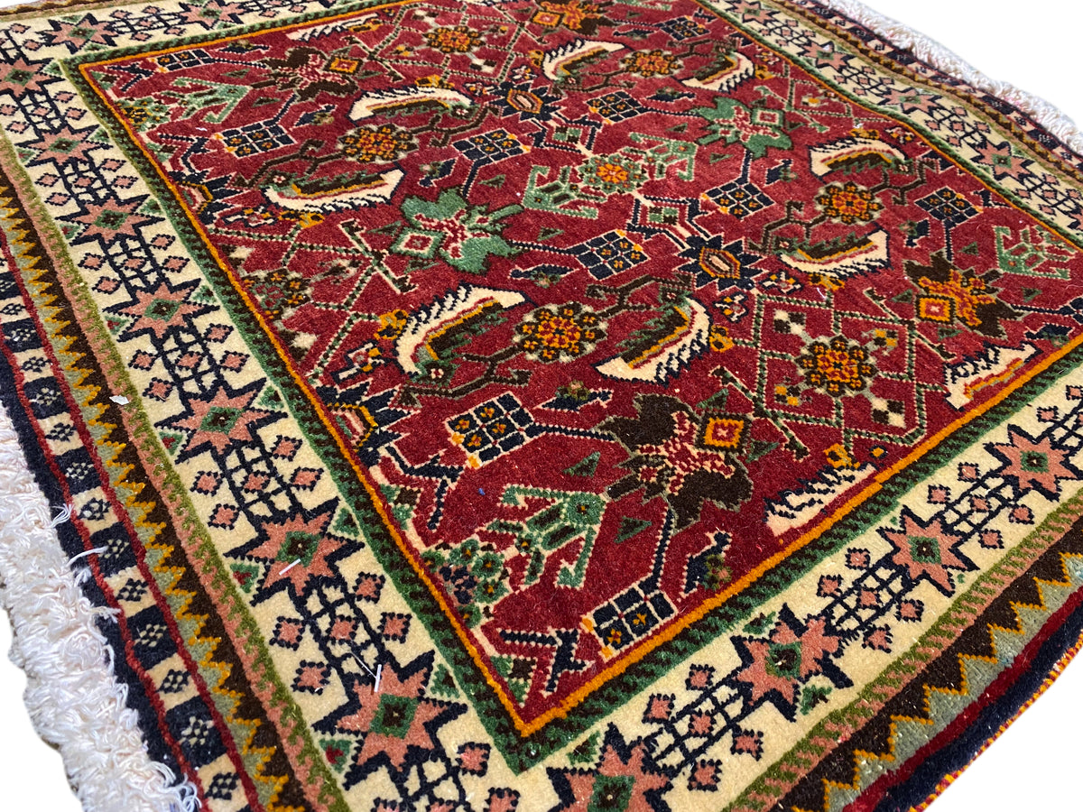 Poshti-Teppich 63x61 cm Detailansicht: rotes Muster mit Tier-/Ornamentmotiven und Bordüre.