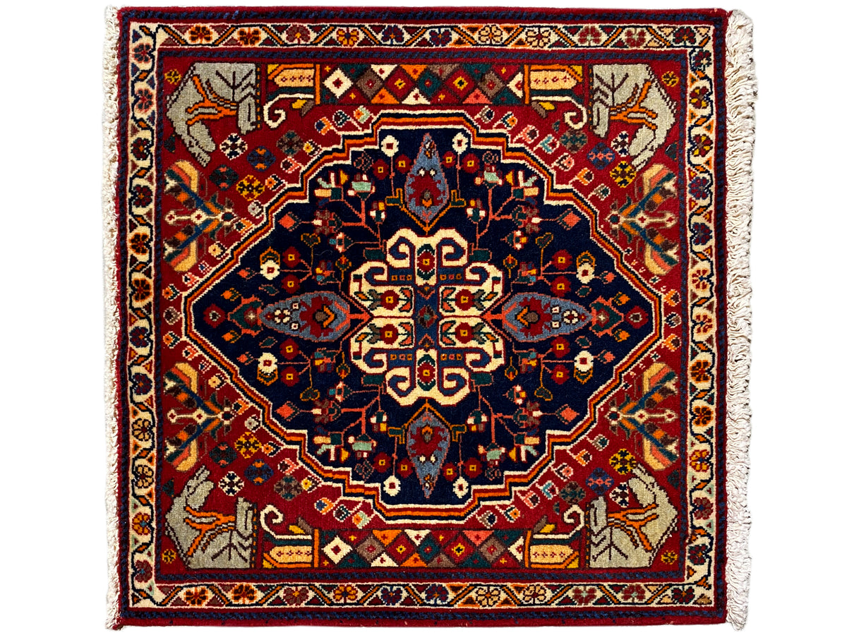 Quadratischer Teppich mit rotem Grund, blauem Musterstern und dekorativen Bordüren