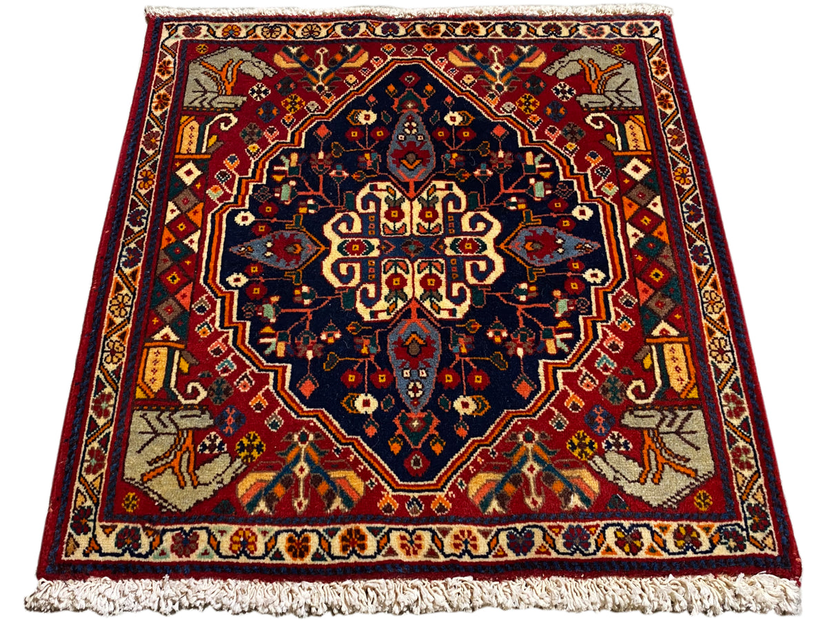 Teppich in Rot und Dunkelblau mit mittigem Ornament, rechteckige Form und Fransen
