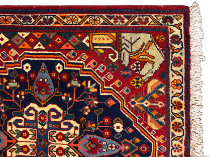 Nahaufnahme vom Teppichrand mit blauem Ornamentfeld, roten Details und Fransen