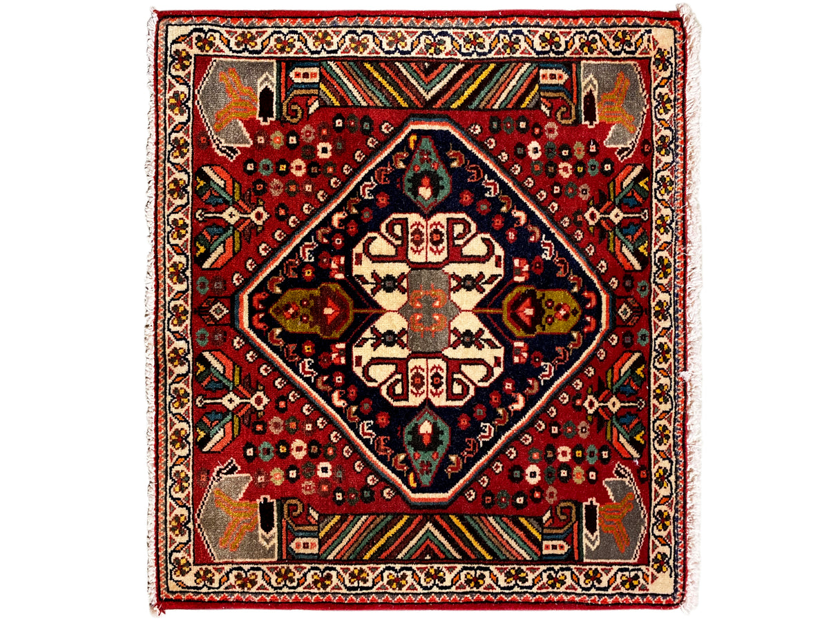 Orientalischer Teppich mit rotem Grund, dunkelblauem Medaillon und geometrischen Ornamenten