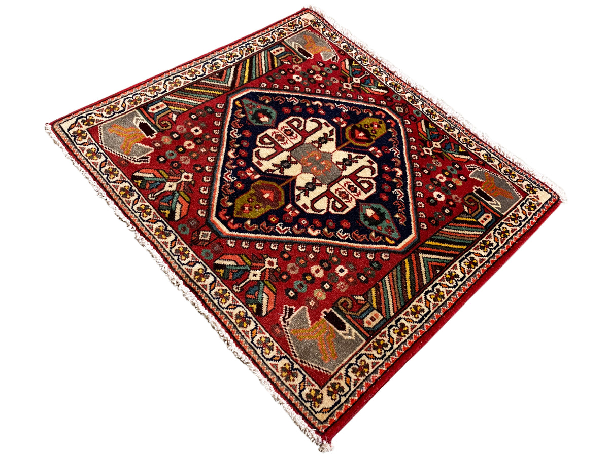 Orientalischer Teppich mit rotem Hintergrund, cremefarbenen Formen und farbigen Zierstreifen