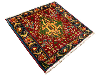 Rechteckiger Teppich (67x66 cm) diagonal fotografiert; rotes Feld, dunkle Einfassung, Fransen