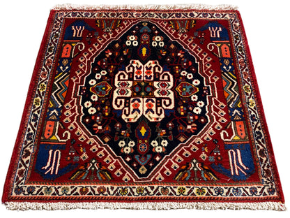 Teppich mit rotem Rand, dunkelblauem Zentrum und mehrfarbigen Ornamente, Fransen