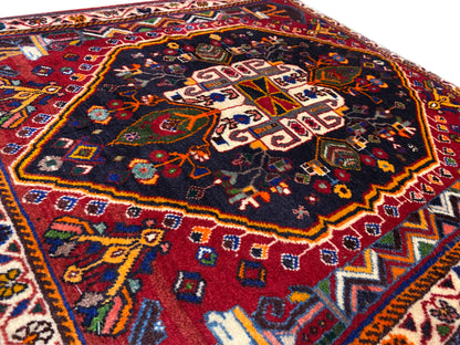Nahaufnahme der Teppichoberfläche mit geometrischem Ornament in Blau, Rot und Gold