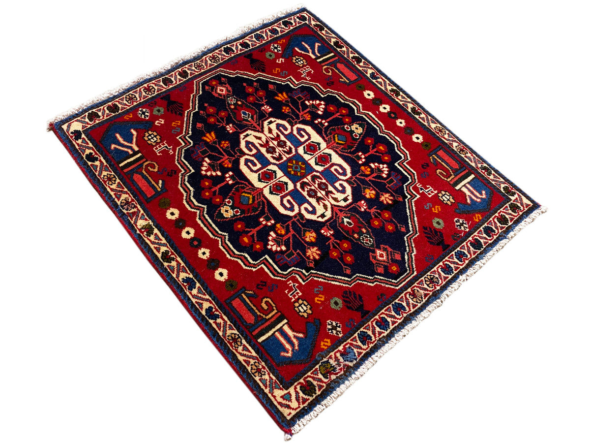 Teppich im Diamant-Layout: rotes Musterfeld mit blauem Rand und Ornamenten